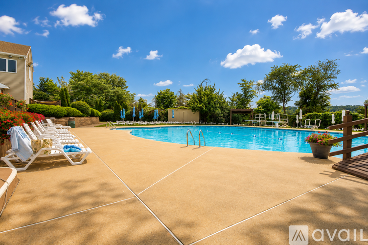 A pool surrounded by a patio and chairs.