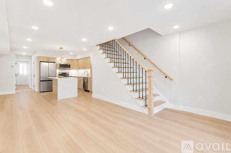 A spacious room with wooden floors and a staircase with a metal railing.