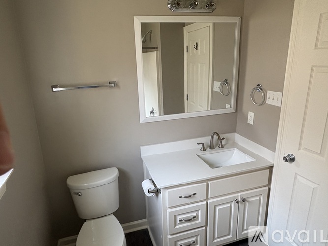 A bathroom with a toilet, sink, and mirror.