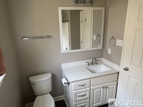 A bathroom with a toilet, sink, and mirror.