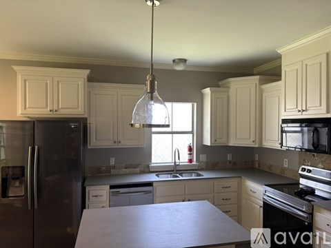 A kitchen with a black refrigerator and white cabinets.