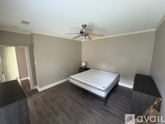 A bedroom with a bed, dresser, and a ceiling fan.