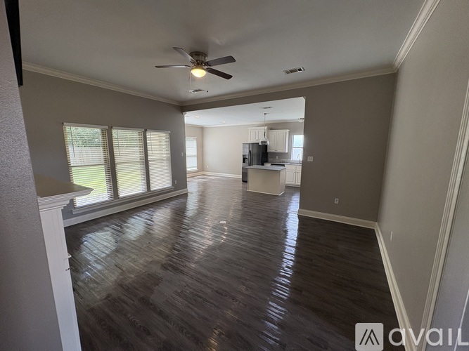 A spacious living room with a ceiling fan and hardwood flooring.