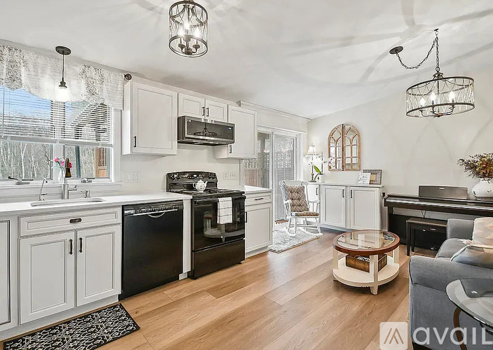 A kitchen with black appliances and wooden floors.