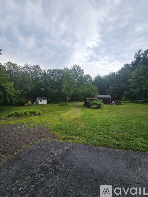 A gravel driveway leads to a house in a grassy yard.