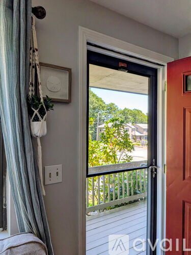 A view of a balcony through a door with a red door on the right.