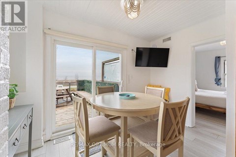 A dining room with a table and chairs and a flat screen TV mounted on the wall.