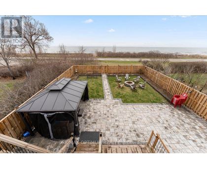A backyard with a patio, a gazebo, and a view of the beach.