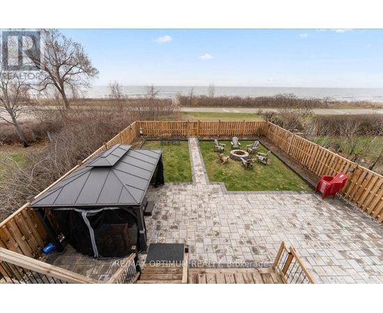 A backyard with a patio, a gazebo, and a view of the beach.