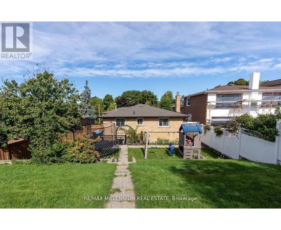 A backyard with a house, a fence, and a tree.