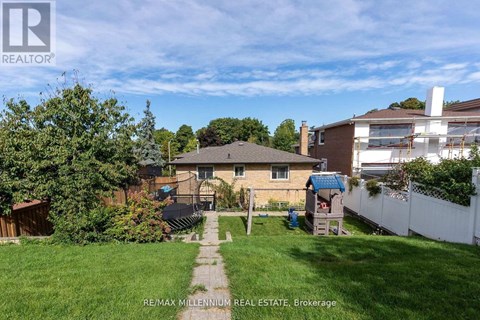 A backyard with a house, a fence, and a tree.