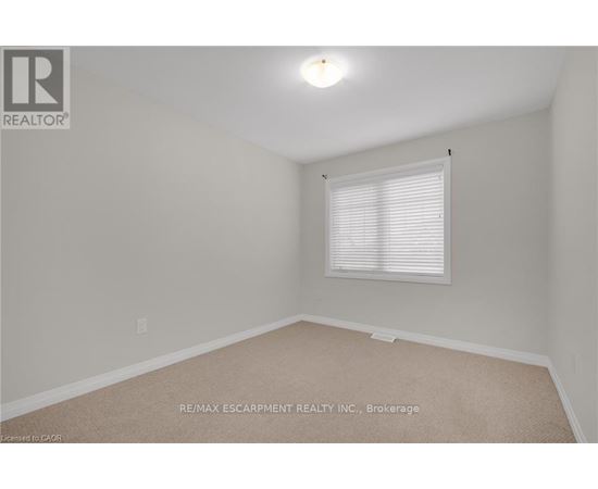 A room with a window and a carpeted floor.