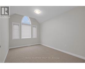 A room with a carpet floor and a window with blinds.