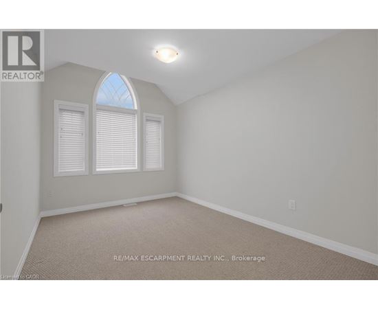 A room with a carpet floor and a window with blinds.