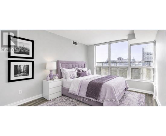 A bedroom with a purple bed and a window overlooking a cityscape.