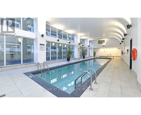 A swimming pool inside a building with a glass enclosure.