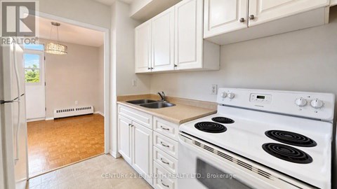 A kitchen with a white stove top oven and white cabinets.
