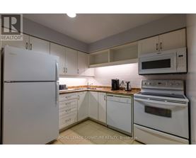 A white refrigerator is in a kitchen with white cabinets and a white oven.