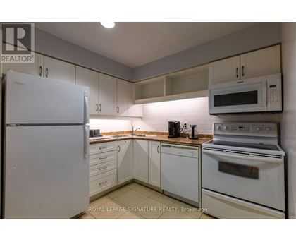A white refrigerator is in a kitchen with white cabinets and a white oven.