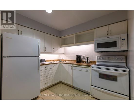 A white refrigerator is in a kitchen with white cabinets and a white oven.