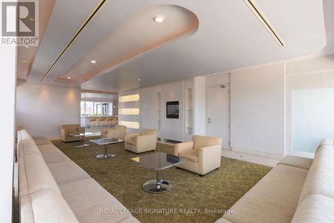 A spacious living room with a white sofa set and a television.