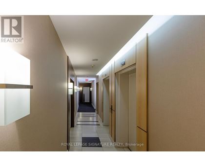 A hallway with doors on the right and a sign that says Royal LePage Signature Realty, Brokerage.