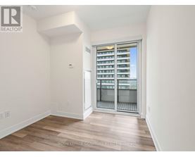 A room with a sliding glass door leading to a balcony with a view of a building.