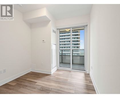 A room with a sliding glass door leading to a balcony with a view of a building.