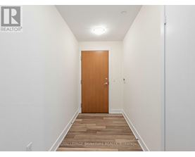 A hallway with a wooden door and a light on the ceiling.