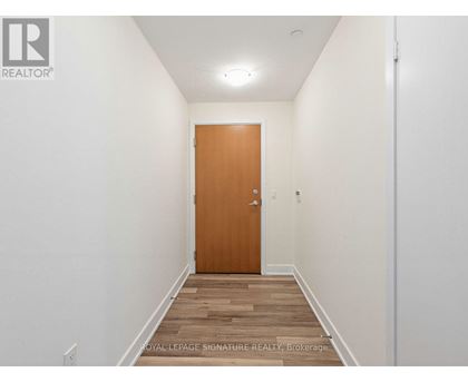 A hallway with a wooden door and a light on the ceiling.