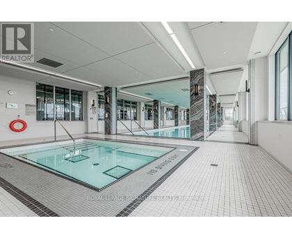 A swimming pool inside a building with a glass wall.