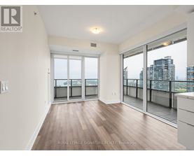 A spacious room with wooden flooring and sliding glass doors leading to a balcony.