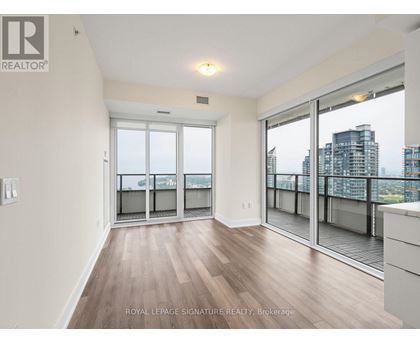 A spacious room with wooden flooring and sliding glass doors leading to a balcony.