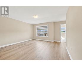 A spacious room with wooden flooring and a large window.