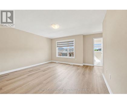 A spacious room with wooden flooring and a large window.