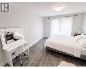 A bedroom with a bed, a vanity table, and a chair.