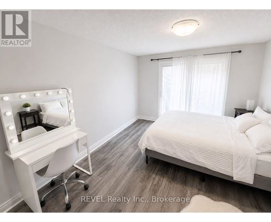 A bedroom with a bed, a vanity table, and a chair.