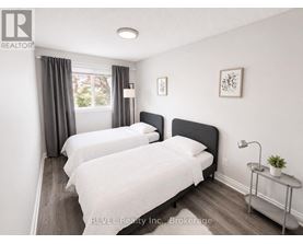 Two beds in a room with REVEL Realty Inc. logo.