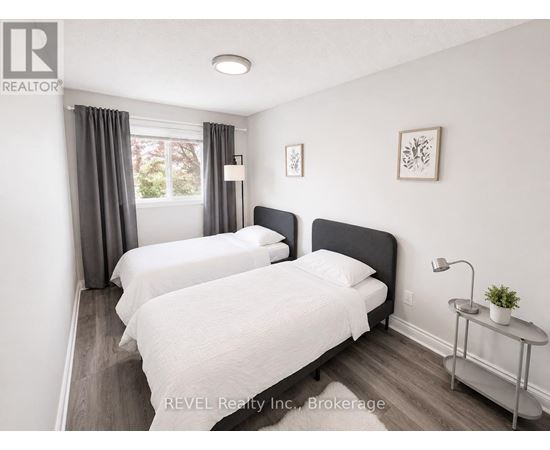 Two beds in a room with REVEL Realty Inc. logo.