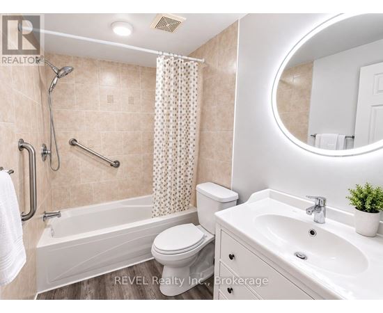 A bathroom with a white toilet, a bathtub with a shower head, a sink, and a round mirror.