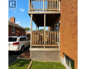 A wooden balcony is attached to a brick building.