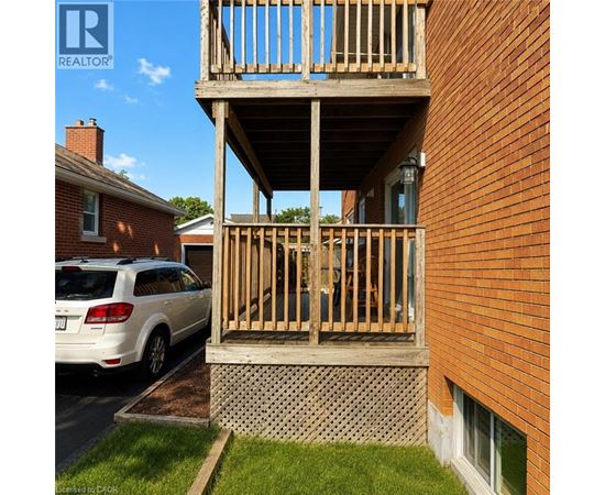 A wooden balcony is attached to a brick building.