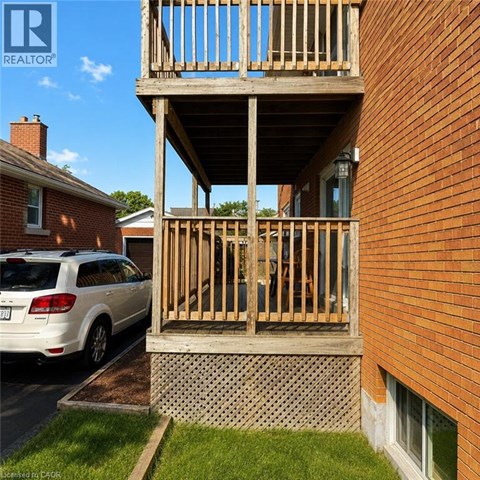 A wooden balcony is attached to a brick building.