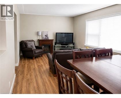 A living room with a brown leather couch, a brown wooden table, and a television.