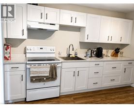 A white kitchen with wooden floors and white cabinets.