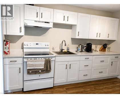 A white kitchen with wooden floors and white cabinets.