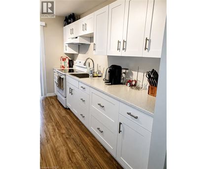 A kitchen with white cabinets and a wooden floor.