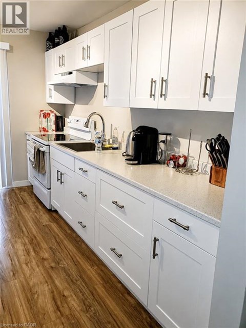 A kitchen with white cabinets and a wooden floor.