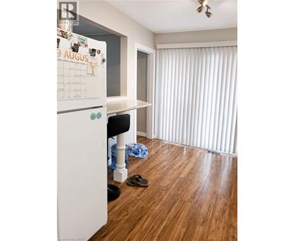 A kitchen with a calendar on the fridge and a wooden floor.