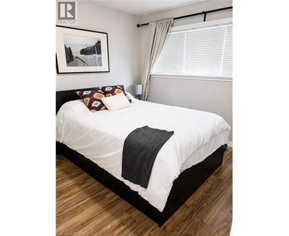 A bedroom with a white bed and a picture on the wall.